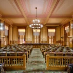 Ornate legislative chamber with wooden desks